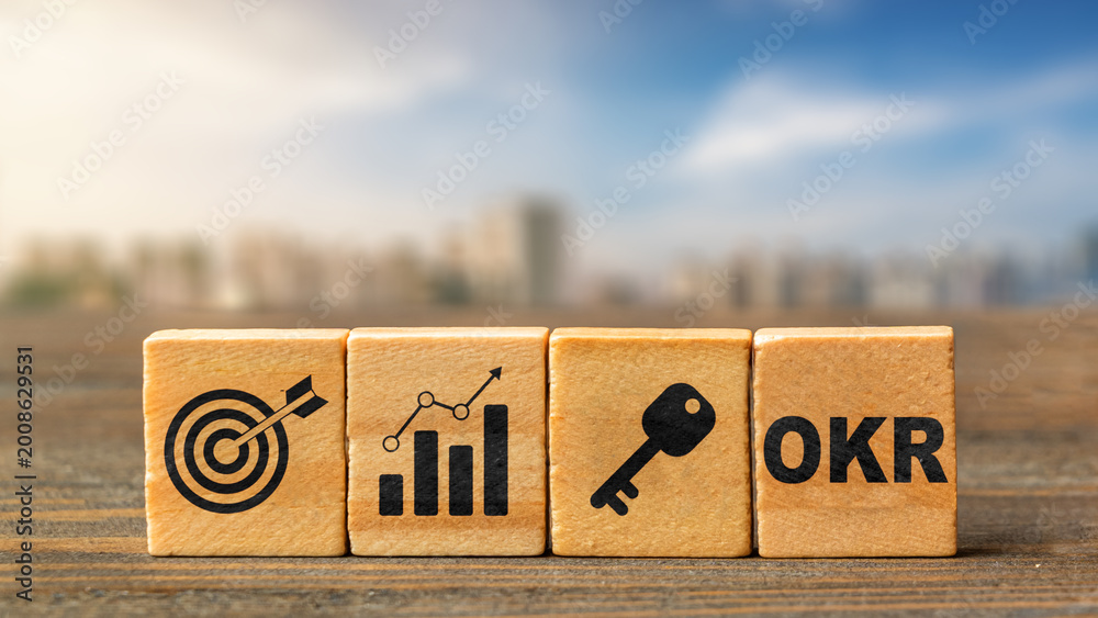 Four wooden blocks showing target, growth chart, key, and OKR text ...