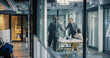 © Gorodenkoff - Business Leaders Complete a Job Interview With a Confident Handshake in a Glass Meeting Room, While a Hiring Manager Reviews Notes and Additional Candidates Wait in the Hallway