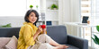 © Fahng - Happy relaxed middle aged asian woman drinking coffee relaxing on sofa at home. Smiling stylish middle aged 50s lady enjoying resting sitting on couch.