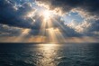 © Halina - Sun rays breaking through dramatic clouds over calm ocean horizon creating golden light reflection