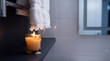 © Olesya - Burning candle near hanging towel in bathroom. Fire hazard risk due to proximity of flammable fabric. Concept of home safety, domestic accident prevention and fire awareness.