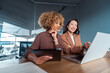 © Stock 4 You - Two professional women collaborating at office desk, reviewing data on laptop and tablet in meeting room, teamwork and business planning. Team of women using technology at work, doing analysing