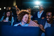 © Marko Geber - Friends laughing and sharing popcorn at movie theater