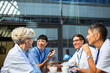 © Marko Geber - Doctors and nurses chatting during coffee break in hospital courtyard