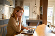 © Davor - Woman working on laptop at home kitchen table