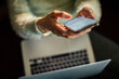 © Davor - Person texting on smartphone over laptop at home