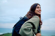 © we.bond.creations - Young woman smiling, looking away while hiking outdoors, enjoying the fresh air and scenic view with a backpack