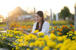 © Apichat - Woman happily caring for marigold flowers in garden at sunset