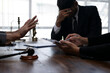 © Wasana - Lawyers discussing and signing legal contract with stressed client in office