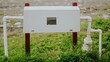 © Наталья Добровольска - Horizontal shot of a white utility enclosure with PVC piping in a grassy field