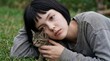 © Everlasting Dreams - A young woman rests on the grass with a kitten, symbolizing a fragile moment of shared vulnerability and the somber, quiet comfort found in a fleeting connection