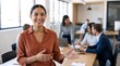 © Vasiliy - Confident businesswoman smiling in a modern open plan office. Welcoming female manager with diverse corporate team in background. Successful teamwork and leadership concept