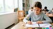 © Xenia - Young girl student drawing a bar graph in a notebook. Elementary school child studying math in classroom