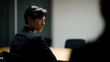 © A2Z AI  - Serious young Asian professional with dark hair in a black suit, looking back during a meeting, conveying focus and contemplation in a corporate setting