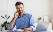 © Prostock-studio - Smiling Businessman Taking Notes While Having Phone Conversation, Sitting At Desk In Modern Office Talking On Cellphone With Client, Checking Business Or Working Schedule In Notepad, Copy Space