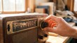 © detry26 - Mans hand tuning vintage radio dial. Retro wooden receiver on desk in cozy room with books. Radio day celebration and classic broadcasting communication concept