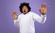 © Prostock-studio - Shocked black guy making protection gesture, feeling frightened on violet studio background, panorama. Terrified African American young man expressing emotion of fear