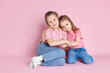 © New Africa - Happy little sisters posing on pink background. Space for text