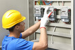 © New Africa - Electrician with screwdriver checking electrical meter indoors