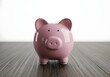 © Yanti - A plump, cheerful pink porcelain porcine money receptacle rests on a wooden surface, signifying savings, domestic finance, and personal wealth accumulation for financial betterment and future