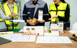 © Nuttapong punna - Engineer teams meeting working together wear worker helmets hardhat on construction site