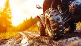 Close-up of muddy ATV tires on a forest dirt road at sunset