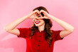 © deagreez - Young woman in red sweater forms heart shape with hands against pink background