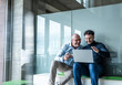 © BusinessClass by W61 - Two businessmen smiling and discussing work with notebook in office