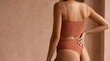 © Riswan - Back rear view close up cropped young lady woman with slim skinny body perfect skin she wear brown ribbed top lingerie stand put hand on buttock on earthy textured wall. Lifestyle beauty fit concept.