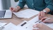 © volha_r - Auditor man wearing green shirt is reviewing papers and using a laptop with the colleague. Business people professionals analyzing financial documents. Finance, audit, and taxes