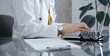 © volha_r - Doctor woman wearing white medical coat over a yellow blouse is working on laptop with stethoscope on the glass desk. Medicine and Health care