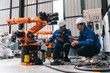 © chokniti - Industrial robot arm auto assembly in factory with engineer teamwork control panel safety helmet inspection training focus