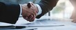 © Nart - Two executives shake hands after signing a business contract in a bright, modern office. The image captures trust, partnership, and successful agreement.