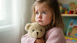 © Nataliia Pyzhova - Sad little girl hugging teddy bear near window, emotional child portrait with soft light and feeling of loneliness and comfort