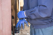 © Alina - Manual worker putting on protective blue nitrile gloves at construction site, highlighting industrial safety standards, manual labor equipment and workplace health risk protection