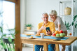© Lumos sp - Portrait of an elderly senior couple having breakfast and using a smart phone at home. Happy healthy affectionate senior couple talking and showing smartphone screen to one another and texting and sit