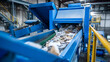 © photo for everything - Industrial waste conveyor belt operating in a modern recycling facility. Blue machinery processes paper and cardboard for environmental sustainability