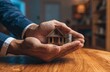 © n0feel_studio - Hands protecting miniature house model and coin stack home insurance and property investment concept indoor setting close-up view financial security