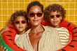 © Georgii - Stylish mother with two children in sunglasses posing with watermelon pool float against yellow tile