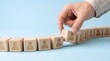 © emwe studio - Human resources management and team building concept. Hand inserting wooden block with employee icon into a wavy row of staff for organizational structure and alignment.
