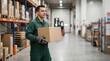 © kodidesign - Delivery worker carrying a cardboard box in a warehouse. Logistics and supply chain concept. Copy space for text