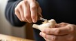 © SashaMagic - Close-up of hands meticulously carving a small wooden bird with a whittling knife, showcasing intricate details and craftsmanship in a serene workshop setting.