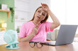 © New Africa - Menopause. Woman suffering from heat flash while working on laptop at table indoors