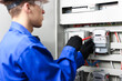 © New Africa - Electrician with screwdriver checking electrical meter indoors, closeup