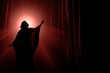 © woters - Silhouetted dancer raises arms toward a glowing red spotlight on stage