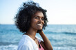 © SISMIZ - Smiling woman with curly hair enjoying a sunny day by the ocean