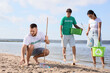 © Pixel-Shot - Group of volunteers cleaning up trash on beach. World Oceans Day