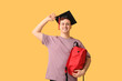 © Pixel-Shot - Male student in mortar board with backpack on yellow background