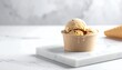 © lemonarts - A delicious ice cream dessert with two scoops sits on a white marble plate next to a cone.
