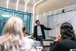 © chokniti - Business meeting presentation chart office conference room presenter pointing graph teamwork discussion professional audience workplace analysis report strategy planning collaboration